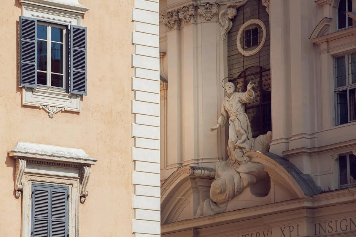 Facciate del centro storico di Roma con persiane e statua barocca